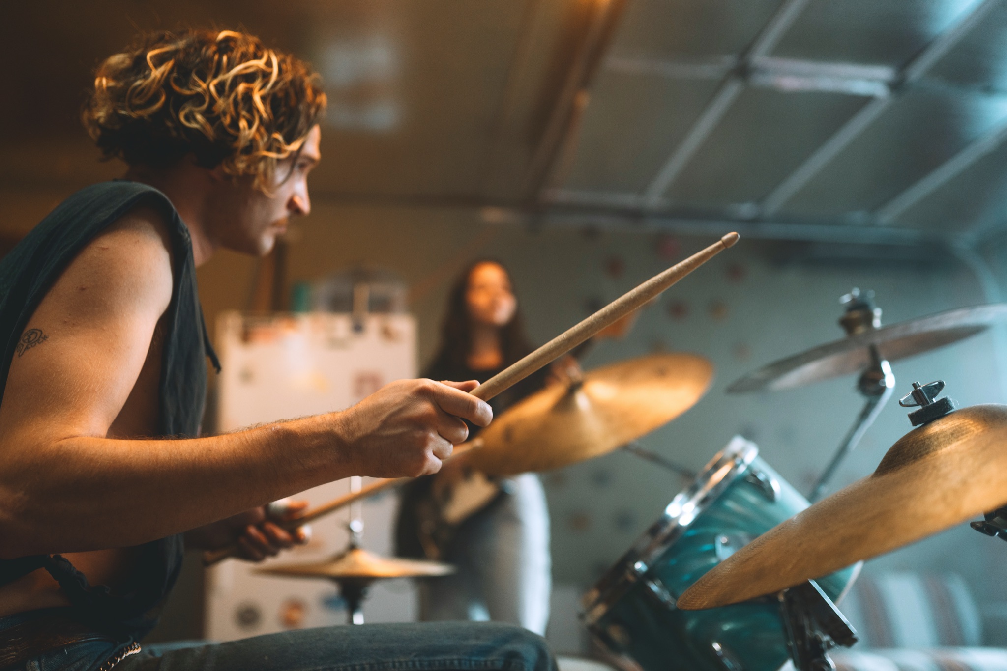 Band rehearsal: the drummer mid-hit, guitarist behind