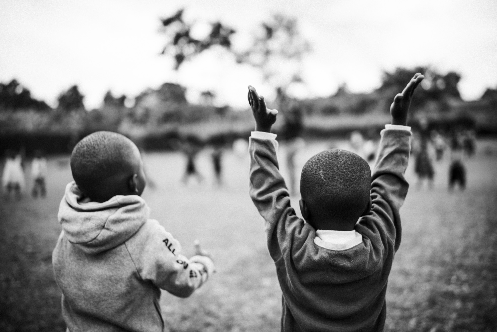 Two kids on the school lawn, hands in the air