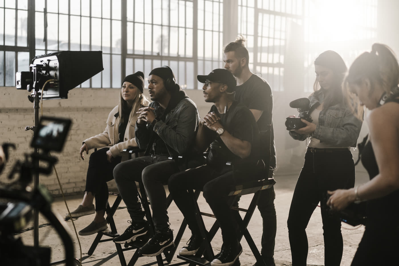 The crew watching playback in the warehouse sun