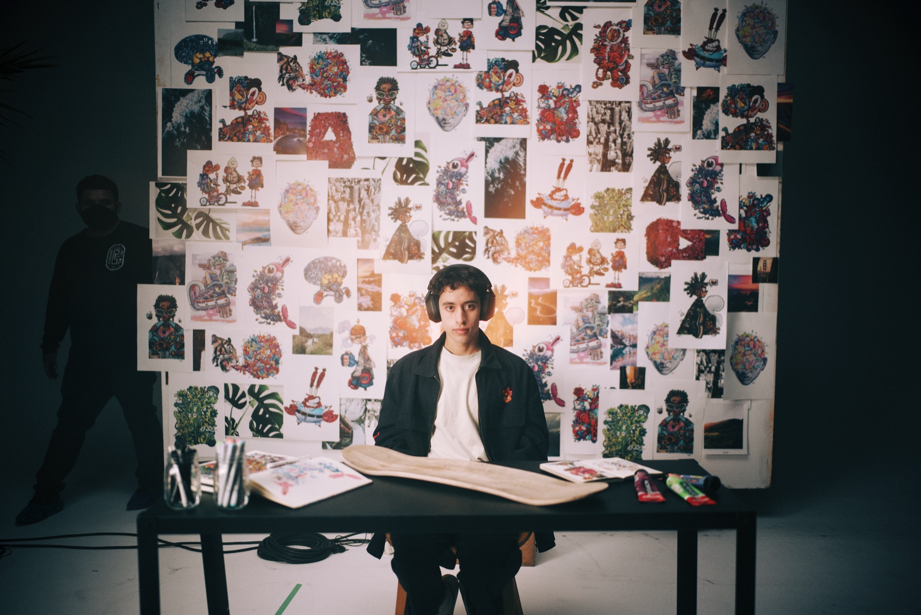 Gawx Art seated at a table in front of his art wall